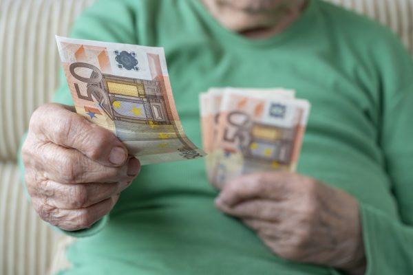 wrinkled hand of a senior woman holding euro banknotes wrinkled hand of a senior woman holding euro banknotes